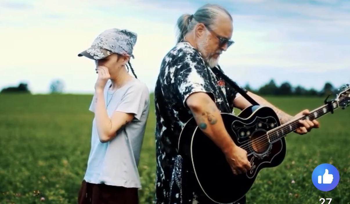 Billy da Kid playing guitar in an open field