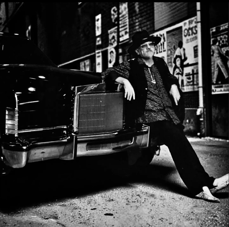 Fast Eddie beside a classic car on a city street