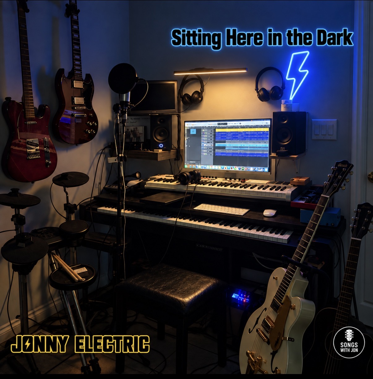 Jonny Electric's studio with guitars, keyboards, electronic drums and the Sitting Here in the Dark title